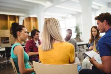 Business executives in meeting People in a circle appearing to be sharing ideas together